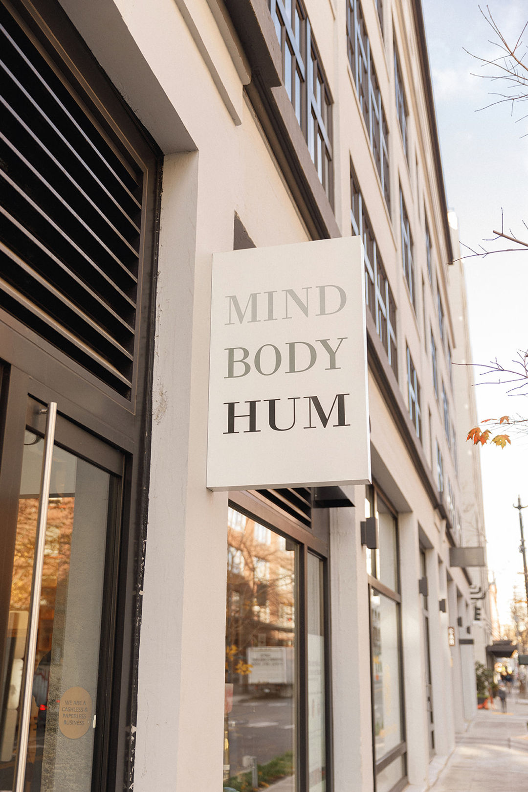 A white sign with the words 'MIND BODY HUM' is mounted on the exterior of a building.