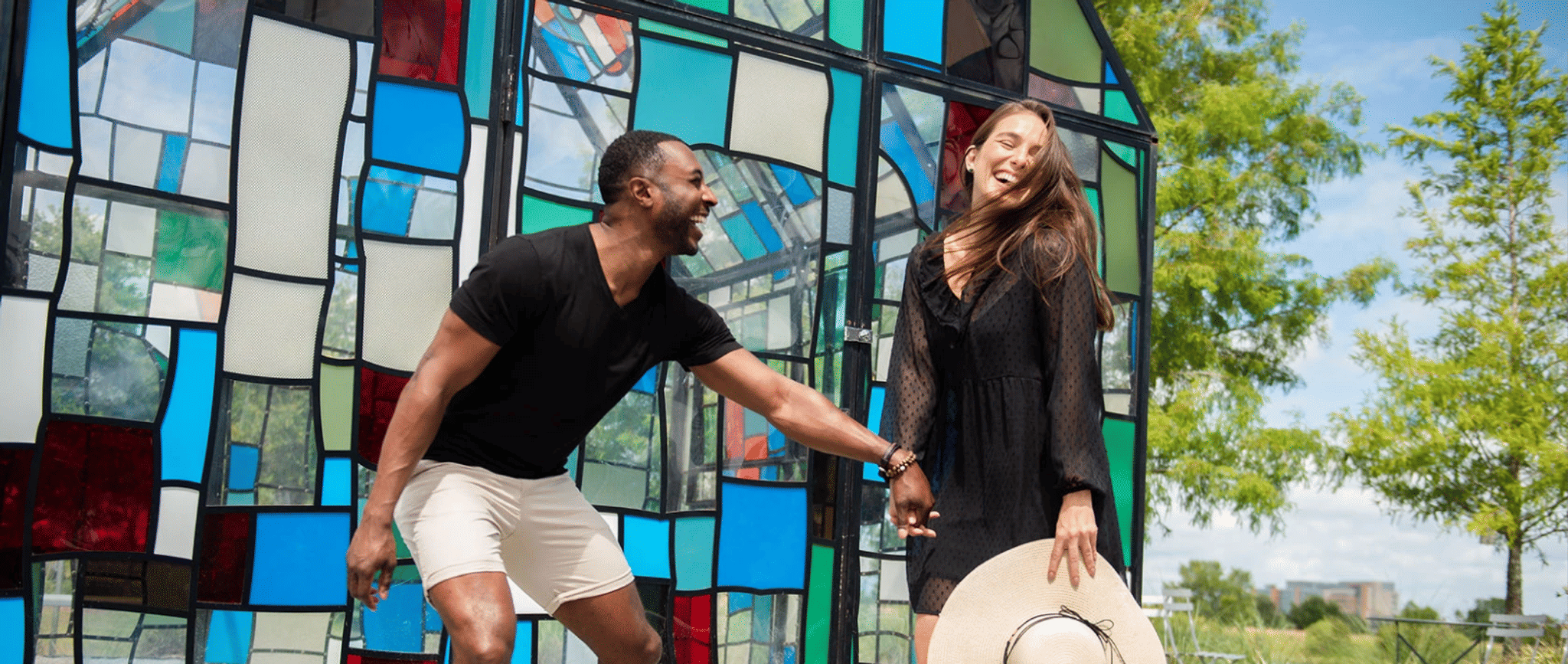 A couple is standing in front of a stained glass wall.