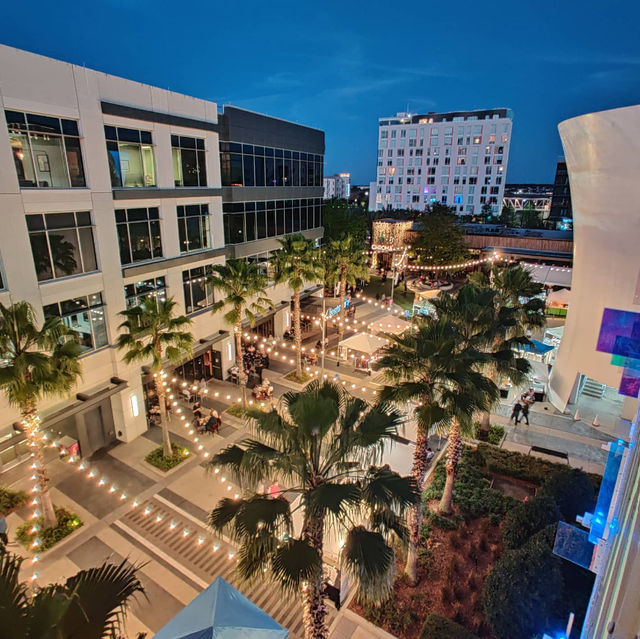 A courtyard with palm trees and string lights at dusk.