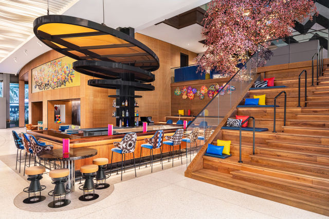 A modern lobby with a bar, stairs, and colorful decor.