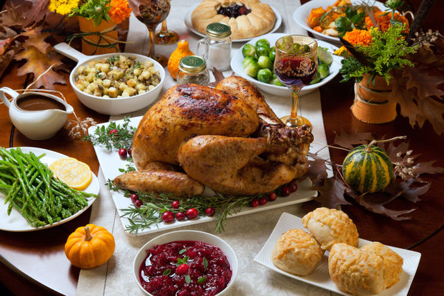 A large spread of food on a table, including a roasted turkey, vegetables, fruits, and other dishes.