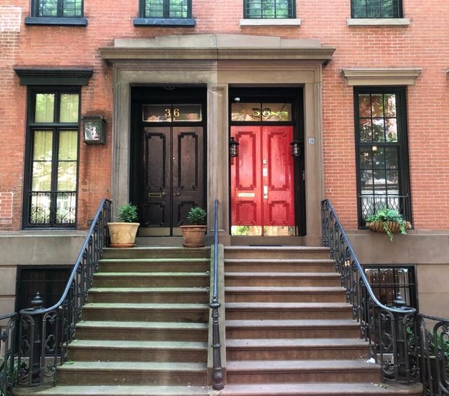 A red brick building with a staircase leading to two sets of doors.