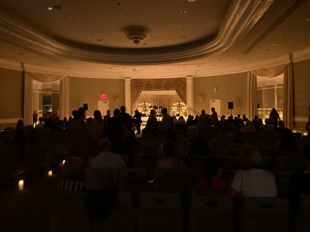 a dimly lit room with people sitting in chairs, facing a stage or bar area